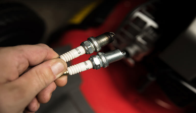 Disconnecting spark plug from a push-mower engine.